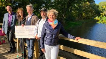 Der Anwohner Axel Rolfs übergibt einen symbolischen Scheck der Spende über 7.000 Euro für den Neubau der Schlossparkbrücke in Rühstädt