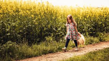 Girl walking alone with teddy and backpack on a field way model released Symbolfoto PUBLICATIONxINxG