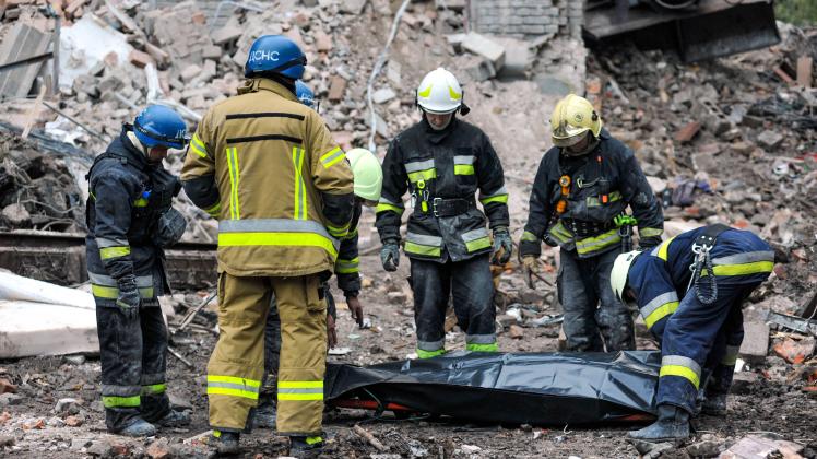 ZAPORIZHZHIA, UKRAINE - OCTOBER 11, 2022 - Rescuers stand over a dead body in a plastic bag during the elimination of co