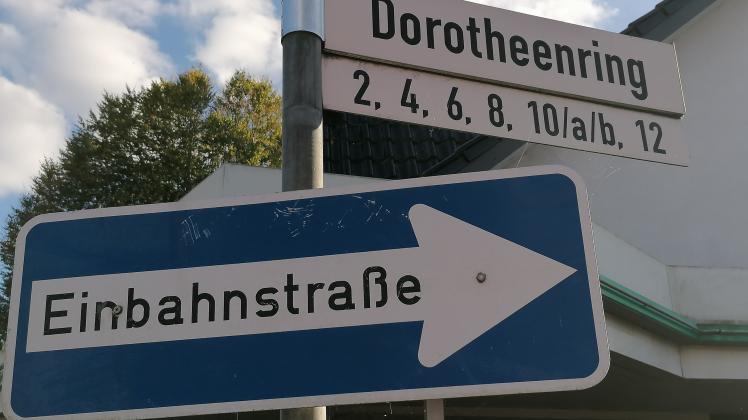 Straßenschild Dorotheenring in Quickborn samt Hinweis auf Einbahnstraße. Dahinter: eine Filiale der Parfumerie Kaland