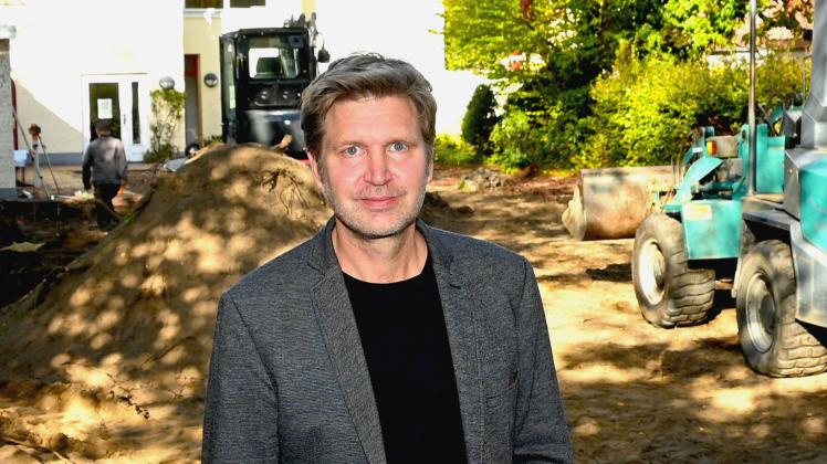 Kulturmanager Oliver Behnecke auf der Baustelle mit dem Kulturhaus Müller im Hintergrund.