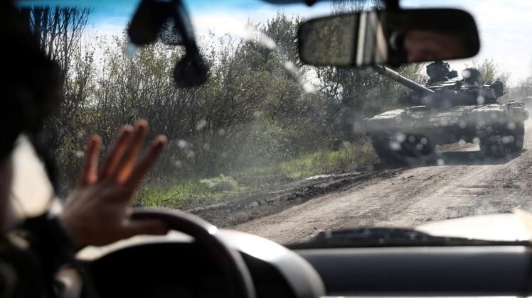 TOPSHOT - A motorist drives by a Ukrainian tank running on a road in Donetsk region, on October 13, 2022, amid Russian invasion of Ukraine. (Photo by Anatolii Stepanov / AFP)