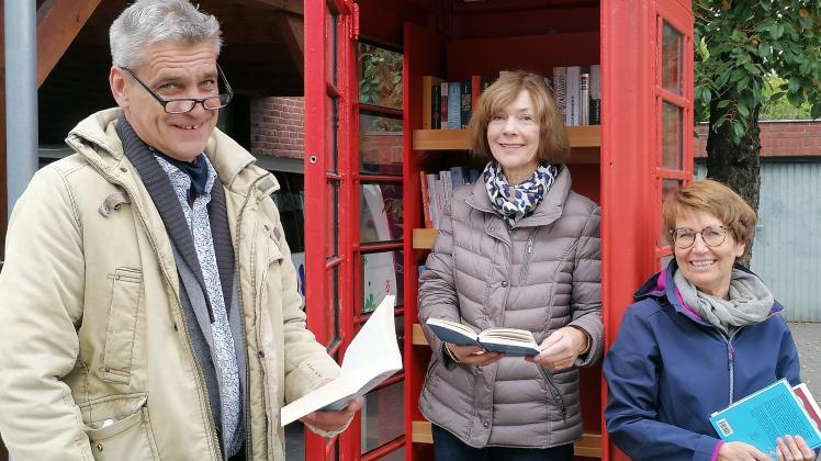Christian Rohde, Hanna Meyer (Mitte) und Birgit Hesse stehen in einer englischen Telefonzelle, in der eine Bücher-Tauschbörse eingerichtet worden ist