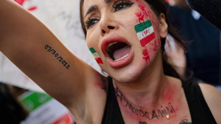 A demonstrator with an Iranian flag painted on her face, shouts slogans as she participates in a rally outside the Iranian consulate in Istanbul on October 17, 2022 after the death of Iranian Mahsa Amini, five weeks ago. - Amini, 22, died on September 16, 2022, three days after she was arrested by Iran&apos;s notorious morality police. (Photo by Yasin AKGUL / AFP)