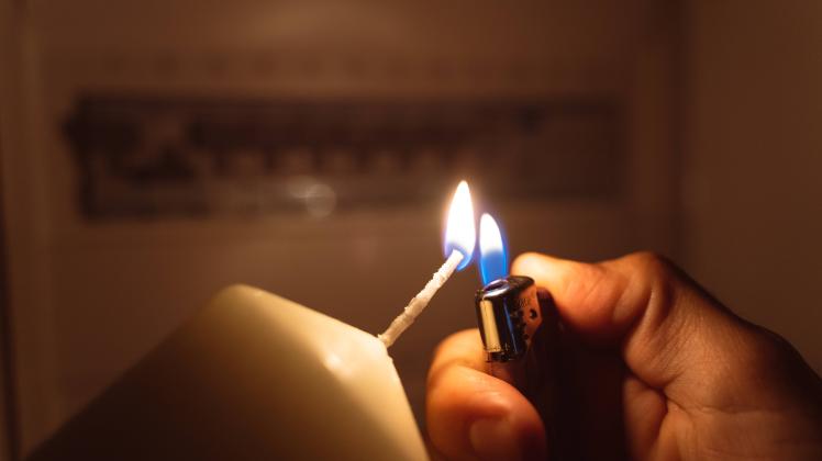 Bavaria, Germany - 25 September 2022: Power failure in the apartment, man lights with candlelight and checks the fuse b