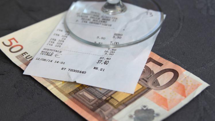 50 Euro Geldschein mit Quittung aus Thermopapier und leerem Glas in einer Gaststaette