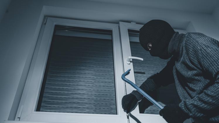 07 October 2022: masked burglar breaks into an apartment with crowbar. Symbol image burglary, theft and robbery *** mask