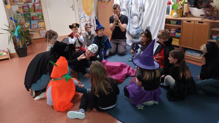 Die Kinder der Kita Rappelkiste in Schwerin gruseln sich gemeinsam mit der Pädagogischen Fachkraft Tobias Oberlies beim Entdecken der Inhalte in der Halloween-Tastkiste.