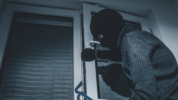 07 October 2022: masked burglar breaks into an apartment with crowbar. Symbol image burglary, theft and robbery *** mask