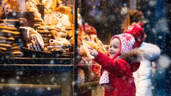 Children window shopping on traditional Christmas market in Germany on snowy winter day. Kids buying candy, pastry and gingerbread in confectionery. Boy and girl choosing sweets in Xmas bakery.