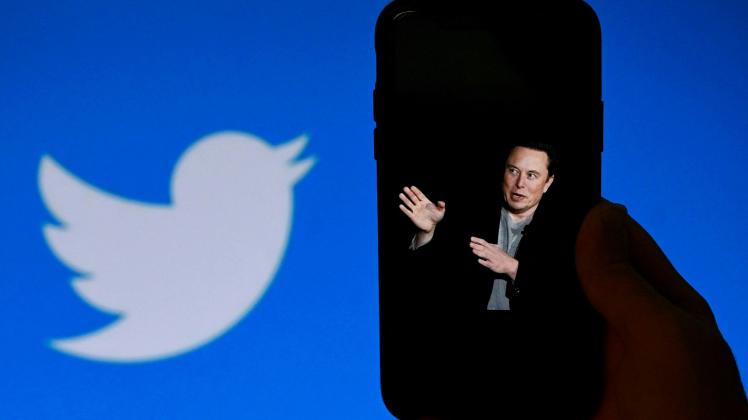 (FILES) In this file photo taken on October 4, 2022, a phone screen displays a photo of Elon Musk with the Twitter logo shown in the background, in Washington, DC. - Twitter said it will start laying off employees on November 4, 2022, as the new billionaire owner Elon Musk moves quickly after his big takeover to make the messaging platform financially sound. (Photo by OLIVIER DOULIERY / AFP)