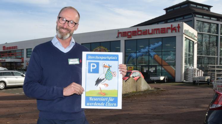 Marktleiter Stefan Lehrke zeigt seinen Entwurf für das künftige „Storchenparkplatz“-Schild für werdende Eltern, dass nach zwei Not-Geburten auf dem Parkplatz des Hagebaumarkts an der B76 aufgestellt werden soll.