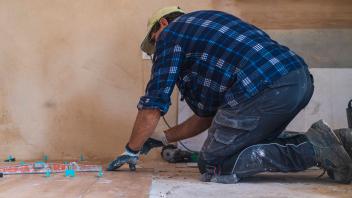 Male manual worker concentrating while working on parquet floor in house model released Symbolfoto property released SNF