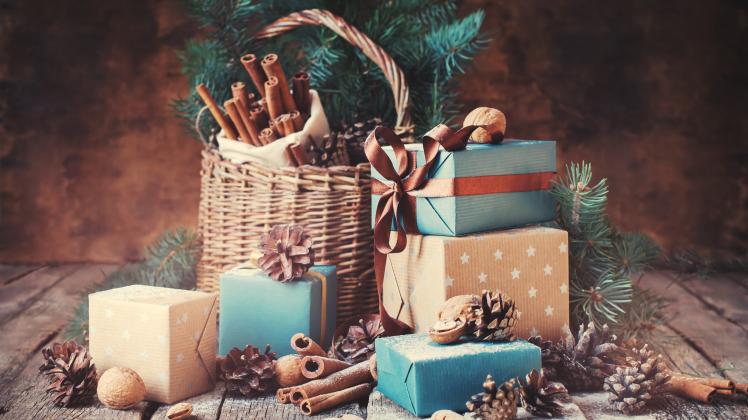 Festive Gifts with Boxes, Coniferous, Basket, Cinnamon, Pine Cones, Wallnuts on Wooden Background