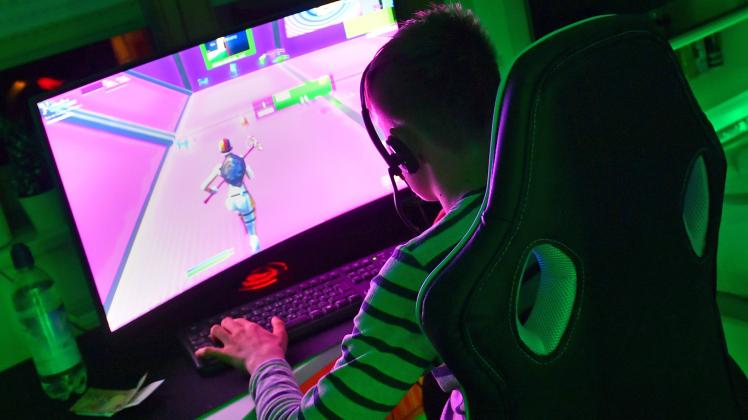Junge (14 Jahre) sitzt nachts in seinem illuminierten Zimmer und spielt an seinem Gaming PC,Computer das Computerspiel F