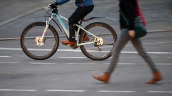 ARCHIV - 21.10.2020, Baden-W rttemberg, Stuttgart: Ein E-Bike-Fahrer  berholt im Morgenverkehr eine Fu ·ngerin. Die Fahrradbranche in Deutschland hat im vergangenen Jahr erneut vom Trend zum E-Bike profitiert. Inzwischen sind eine Menge Leute mit Fahrr·der