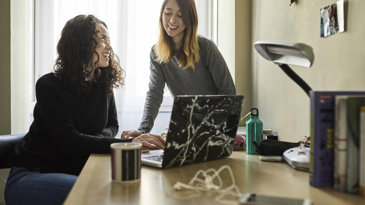 Two young women sharing laptop at home model released Symbolfoto property released PUBLICATIONxINxGE