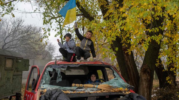 TOPSHOT - A young boy stands on a destroyed car, waving a Ukrainian flag, at a former Russian checkpoint at the entrance of Kherson as local residents celebrate the liberation of the city, on November 13, 2022, amid Russia&apos;s invasion of Ukraine. - Ukrainians in the liberated southern city of Kherson expressed a sense of relief on November 11, 2022, after months of Russian occupation. There were no scenes of jubilation on November 13, 2022, an AFP correspondent said, but many locals said they felt a great sense of relief after Kyiv had wrested back control of the city. (Photo by AFP)