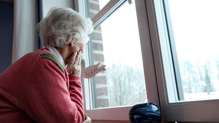 Eine Seniorin schaut aus dem Fenster