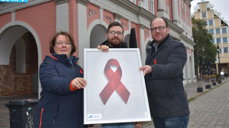 Die Rote Schleife ist weltweit das Symbol der Solidarität mit HIV-Infizierten und AIDS-Kranken. Auch Claudia Röske, Sachbearbeiterin im Rostocker Büro für Gleichstellung, Robert Holz und Sozialsenator Steffen Bockhahn (v. l.) demonstrieren diese Solidarität.