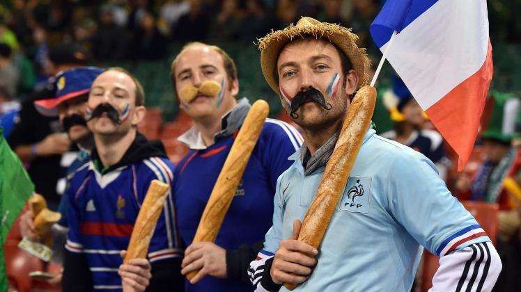 (FILES) In this file photo taken on October 11, 2015, French rugby fans hold baguettes as they pose for a photograph ahead of a Pool D match of the 2015 Rugby World Cup between France and Ireland at the Millennium Stadium in Cardiff, south Wales. - The French baguette was given UNESCO World Heritage status on November 29, 2022, as the UN agency granted "intangible cultural heritage status" to the tradition of making the baguette and the lifestyle that surrounds them. (Photo by Gabriel BOUYS / AFP)