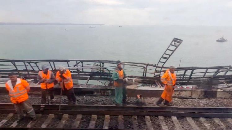 This video grab taken from footage provided by a train passenger shows workers restoring the railway tracks on the Kerch bridge that links Crimea to Russia, near Kerch, on October 9, 2022, a day after it was damaged by a blast. - The symbolic bridge inaugurated by Russia's President Vladimir Putin in 2018,  is logistically crucial for Moscow, a vital transport link for carrying military equipment to Russian soldiers fighting in Ukraine. (Photo by AFP)