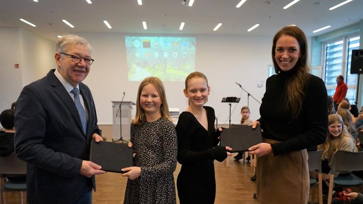 Bürgermeister Hartmut König und Klassenlehrerin Merle Blunk übergeben Marla Richter (Klasse 5c,Zweite von links)
und Leonie Cohrt aus der Klasse 5b ihre neuen Tablets.