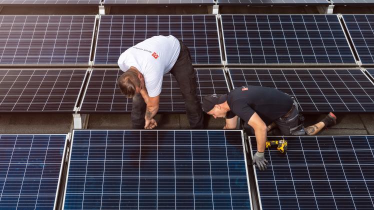Die Nachfrage boomt: Mitarbeiter von Meyer Technik installieren eine Solaranlage auf einem Flachdach.