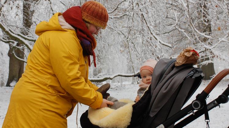 Im Schlosspark hilft Sherin Clausen ihrer Tochter in die Winterschuhe. Zum ersten Mal in ihrem Leben wird die Kleine im Schnee spielen.