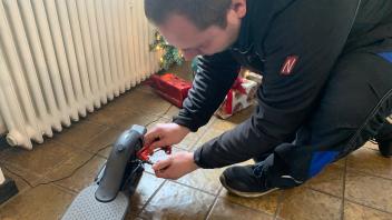 Steffen Bertram bringt ein Bremsscheibenschloss an einem E-Scooter an.