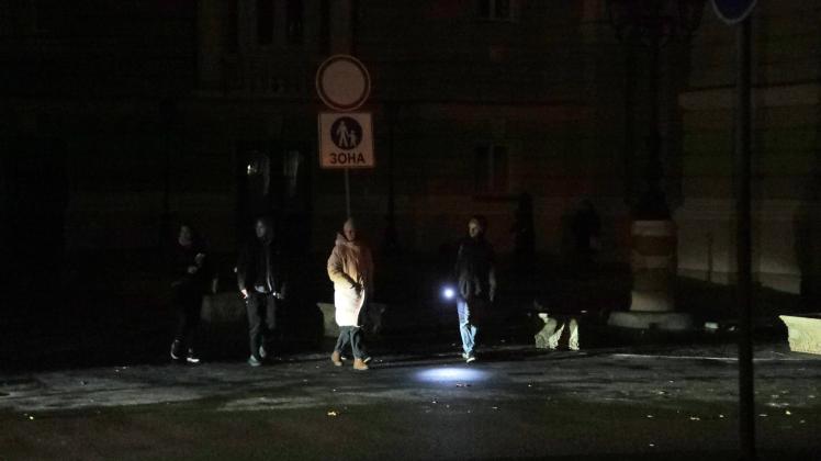 ODESA, UKRAINE - DECEMBER 5, 2022 - Pedestrians cross a dark street as the city experiences power cuts after the massive