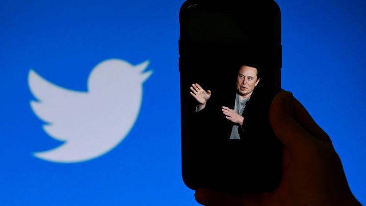 (FILES) In this file photo taken on October 4, 2022, a phone screen displays a photo of Elon Musk with the Twitter logo shown in the background, in Washington, DC. - Twitter suspended December 15, 2022, the accounts of more than a half-dozen journalists who had been writing about the company and its new owner Elon Musk. Some of the journalists had been tweeting about Twitter shutting down an @ElonJet account that tracked flights of the billionaire's private jet and about versions of that account hosted at other social networks. (Photo by OLIVIER DOULIERY / AFP)