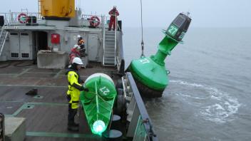 Eine Leuchttonne liegt im Wasser, eine Wintertonne noch an Deck. Insgesamt tauschten die Arbeiter 36 Tonnen aus, um die Seefahrtswege vor Nordfriesland fit für den Winter zu machen.