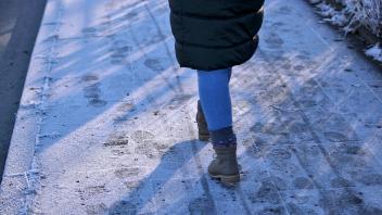 17.12.2022, Wuppertal, Der Gehweg ist mit einer Schicht aus Frost, Raureif, Eis und Schnee bedeckt. Fußgänger haben Fußs