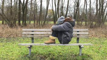 Junge Frau traurig und enttaeuscht auf einer Parkbank im Wald sitzend am 01 02 2016 in Muenchen Deu