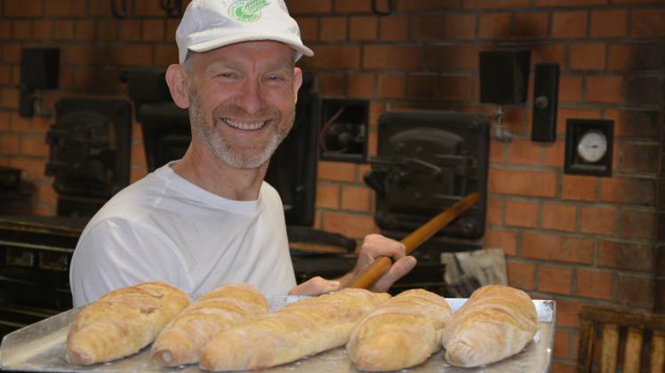 Bäckermeister Christian Fries holt frische Bio-Baguettes aus dem Ofen.