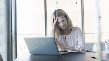 Stressed businesswoman using laptop in office model released Symbolfoto property released PUBLICATIONxINxGERxSUIxAUTxHU