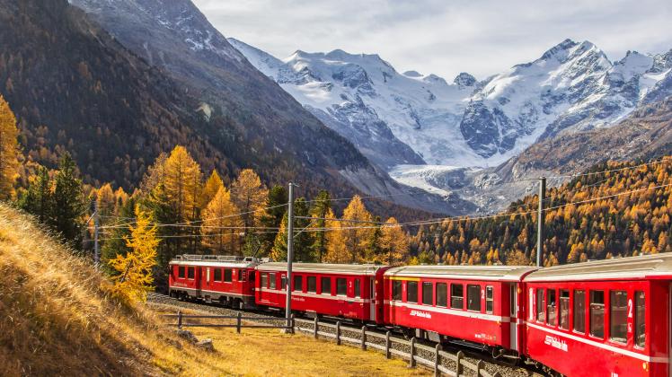 A red passenger train with Bernina massif and Morteratsch Glacier