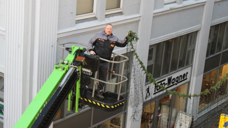 Mario Esch montiert in fünf Meter Höhe die Lichterketten in der Rendsburger Fußgängerzone ab