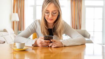 junge Frau liest zuhause Nachrichten in ihrem Handy, München, Januar 2023 Deutschland, München, Januar 2023, junge Frau 