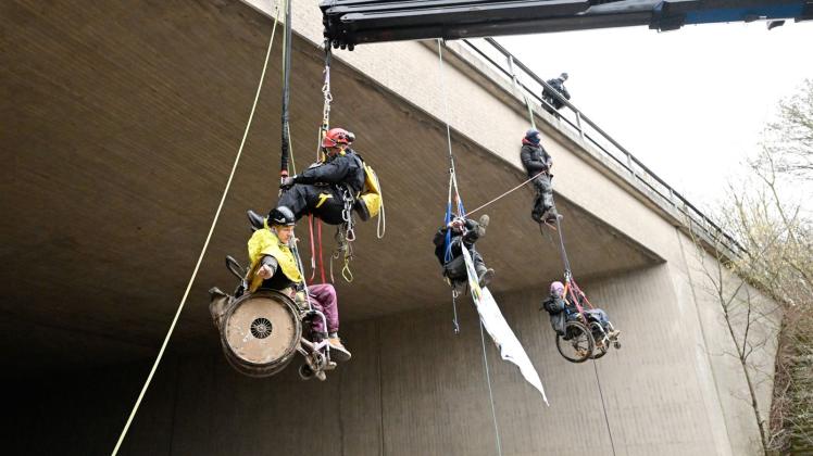 Klimaaktivisten in Rollstuhl seilen sich von Brücke ab