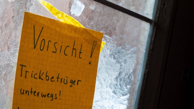 Vorsicht Trockbetrüger unterwegs! - Handschriftliche Warnung vor möglichen Trickbetrügern an einer Berliner Haustür. / C