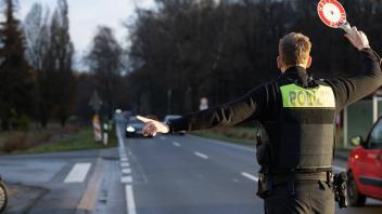 Deutschland 07. Dezember 2022: Ein Beamter der Polizei steht mit einer Polizeikelle, Winkerkelle, mit der Aufschrift - H