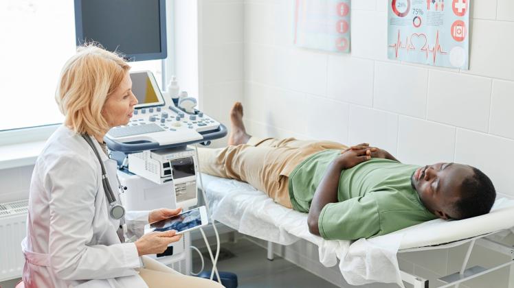 Doctor talking with patient lying on bed doing ultrasound in clinic model released, Symbolfoto property released, DSHF00