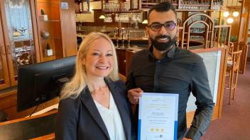 Cindy Lehmann und Juan Alibrahim präsentieren an der Rezeption stolz das neue 3-Sterne-Zertifikat für ihr Hotel Goldenstedt in Delmenhorst. 