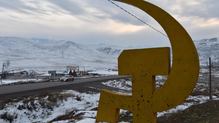 This photograph taken on December 12, 2022, shows a Soviet era hammer and sickle sign instaled in front of the entrance to the town of Suluktu, some 1100 km from Bishkek, Kyrgyzstan. - Nestled in the foothills of mountain ranges, the city of Suluktu, founded in 1868, is one of the oldest coal mining centres in Central Asia. Thanks to growing demand from Kyrgyztan's Central Asian neighbours, as well as China and Europe, there are hopes the Suluktu mines will return to their Soviet heyday. (Photo by VYACHESLAV OSELEDKO / AFP)
