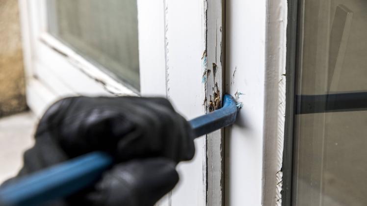 Symbolbild Wohnungseinbruch Täter versucht in eine Wohnung einzubrechen hebelt ein Fenster mit Wer