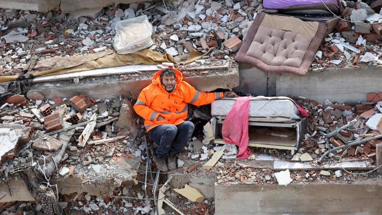 TOPSHOT - Mesut Hancer holds the hand of his 15-year-old daughter Irmak, who died in the earthquake in Kahramanmaras, close to the quake's epicentre, the day after a 7.8-magnitude earthquake struck the country's southeast, on February 7, 2023. - Rescuers in Turkey and Syria braved frigid weather, aftershocks and collapsing buildings, as they dug for survivors buried by an earthquake that killed more than 5,000 people. Some of the heaviest devastation occurred near the quake's epicentre between Kahramanmaras and Gaziantep, a city of two million where entire blocks now lie in ruins under gathering snow. (Photo by Adem ALTAN / AFP)