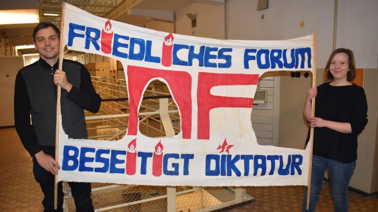 Dieses Original-Banner aus der Wendezeit in Rostock ist eines der Exponate in der neuen Ausstellung in der Dokumentations- und Gedenkstätte Rostock, hier präsentiert von Steffi Brüning und Carsten Socke. 