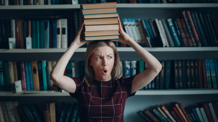 Young beautiful blond student woman girl with pile books